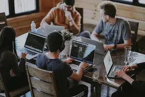 A group of people sitting together working on laptops.